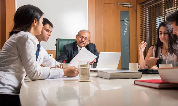 Combinando su experiencia. Joven y guapo empresario y mujer india haciendo gestos y discutiendo algo con sus compañeros de trabajo mientras están sentados en la mesa de la oficina, enfoque selectivo — Foto de Stock