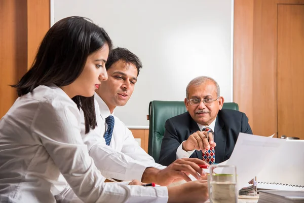 Combinando su experiencia. Joven y guapo empresario y mujer india haciendo gestos y discutiendo algo con sus compañeros de trabajo mientras están sentados en la mesa de la oficina, enfoque selectivo — Foto de Stock