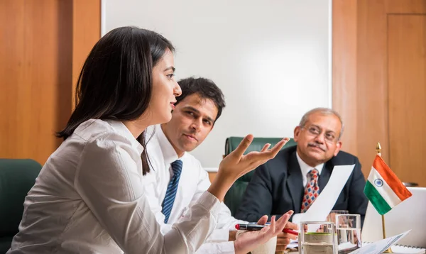 Combinando su experiencia. Joven y guapo empresario y mujer india haciendo gestos y discutiendo algo con sus compañeros de trabajo mientras están sentados en la mesa de la oficina, enfoque selectivo — Foto de Stock