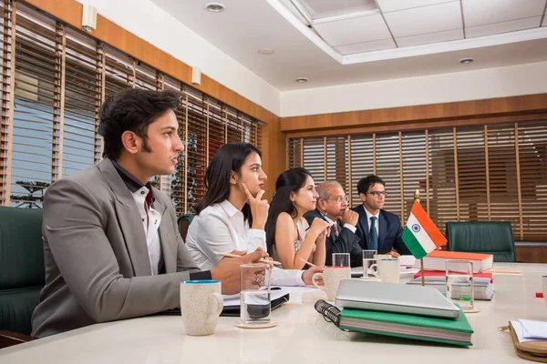 Group Of Indian Businesspeople In Video Conference or at presentation or listening to a sales speech At Business Meeting, with a miniature indian flag post over table