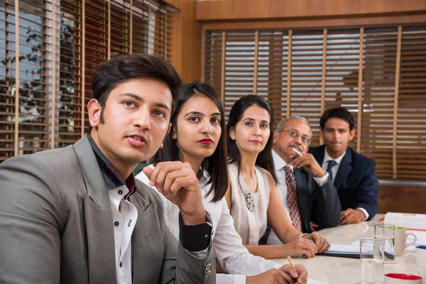 Grupo de empresarios indios en videoconferencia o en la presentación o escuchando un discurso de ventas en la reunión de negocios, con un puesto de bandera india en miniatura sobre la mesa — Foto de Stock