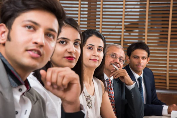 Grupo de empresarios indios en videoconferencia o en la presentación o escuchando un discurso de ventas en la reunión de negocios, con un puesto de bandera india en miniatura sobre la mesa — Foto de Stock