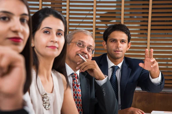 Grupo de empresarios indios en videoconferencia o en la presentación o escuchando un discurso de ventas en la reunión de negocios, con un puesto de bandera india en miniatura sobre la mesa — Foto de Stock