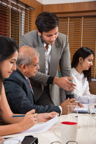 Combinando su experiencia. Joven y guapo empresario y mujer india haciendo gestos y discutiendo algo con sus compañeros de trabajo mientras están sentados en la mesa de la oficina, enfoque selectivo — Foto de Stock