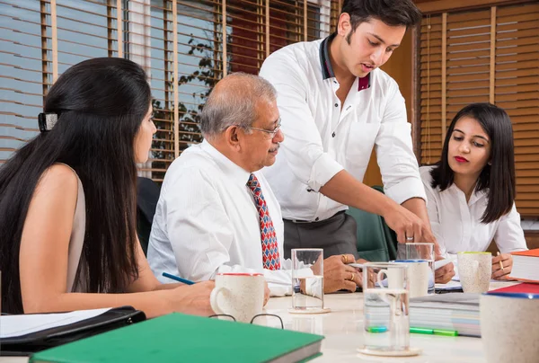 Combinando su experiencia. Joven y guapo empresario y mujer india haciendo gestos y discutiendo algo con sus compañeros de trabajo mientras están sentados en la mesa de la oficina, enfoque selectivo — Foto de Stock