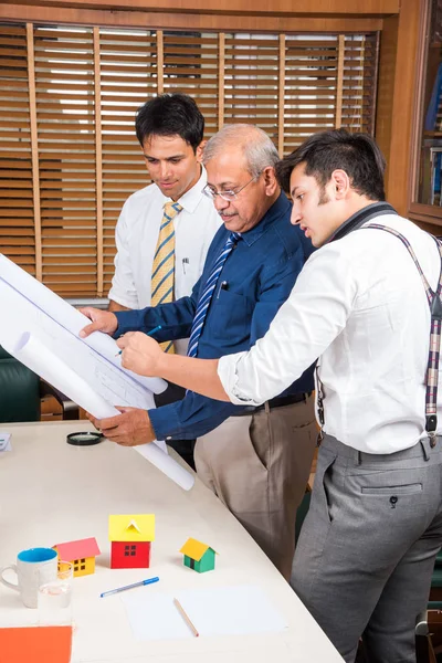 Equipo de arquitectos indios discutiendo el proyecto de vivienda con el modelo y plan de construcción, en casa, enfoque selectivo — Foto de Stock