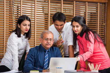 Yeni plan memnun. Gençlerin Grup 4-5 Hint neşeli ve gülümseme yaslanmış ofiste tabloda için süre ile laptop arıyorum bir deneyimli iş adamı