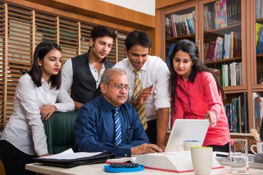 Yeni plan memnun. Gençlerin Grup 4-5 Hint neşeli ve gülümseme yaslanmış ofiste tabloda için süre ile laptop arıyorum bir deneyimli iş adamı