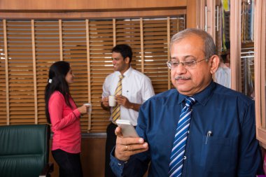 Kahve içer ve arka planda tartışırken 2 genç iş adamları ise cebinde silah ile ayakta Hint yakışıklı üst düzey iş adamı