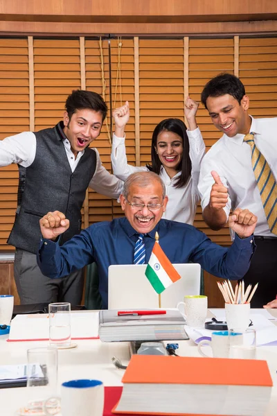 Indian business people enjoying success in conference room with throwing papers in the air, either stock market or cricket or sports victory celebration in office