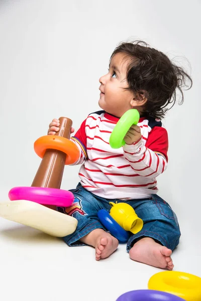 Indian or asian small baby playing with toys or blocks over white background, toddler playing with toys, isolated and selective focus — Stock Photo, Image