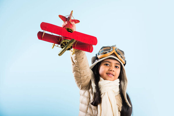 Happy Indian or asian girl kid playing with toy metal airplane against winter sky background - Kid and flying or ambition concept