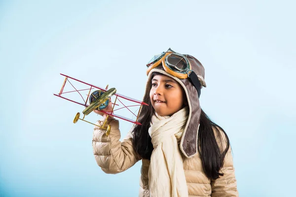 Happy Indian or asian girl kid playing with toy metal airplane against winter sky background - Kid and flying or ambition concept — Stock Photo, Image