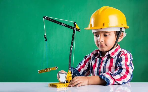Bonito indiana bebê menino brincando com brinquedo guindaste vestindo amarelo chapéu de construção ou chapéu duro, infância e educação conceito — Fotografia de Stock
