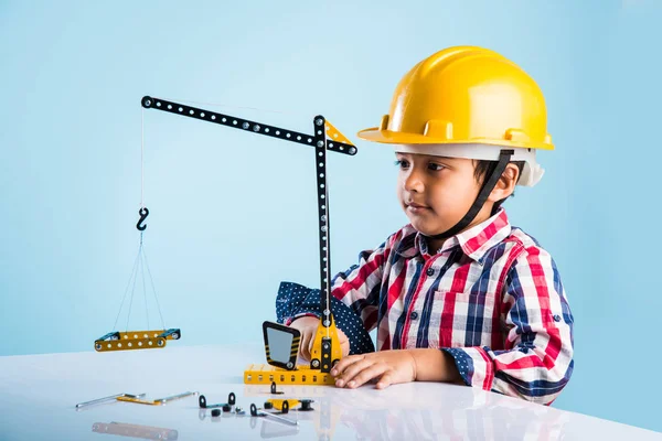 Bonito indiana bebê menino brincando com brinquedo guindaste vestindo amarelo chapéu de construção ou chapéu duro, infância e educação conceito — Fotografia de Stock