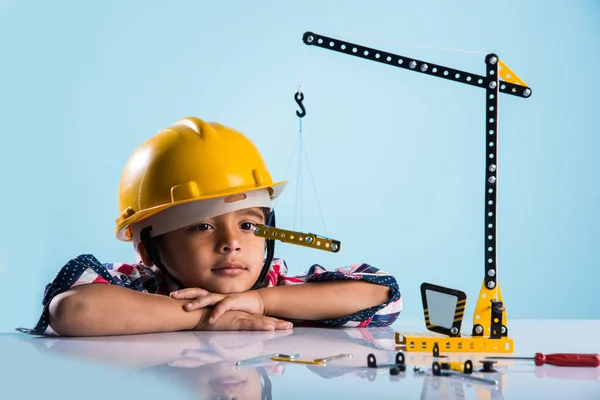 Bonito indiana bebê menino brincando com brinquedo guindaste vestindo amarelo chapéu de construção ou chapéu duro, infância e educação conceito — Fotografia de Stock