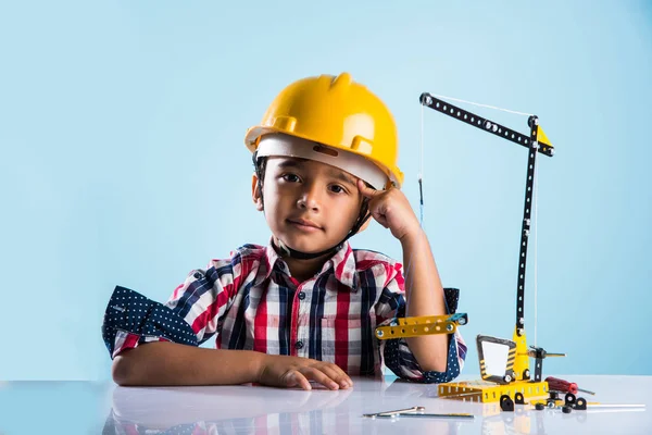 Bonito indiana bebê menino brincando com brinquedo guindaste vestindo amarelo chapéu de construção ou chapéu duro, infância e educação conceito — Fotografia de Stock