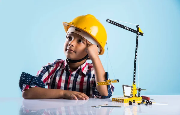 Bonito indiana bebê menino brincando com brinquedo guindaste vestindo amarelo chapéu de construção ou chapéu duro, infância e educação conceito — Fotografia de Stock