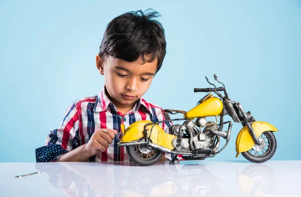 Indian small kid playing or repairing a toy motor bike or minibike — Stock Photo, Image