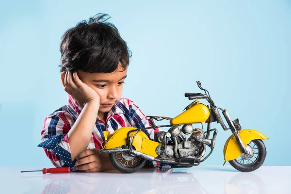 Niño pequeño indio jugando o reparando una moto de juguete o una minibicicleta — Foto de Stock