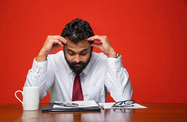 Frustrado joven empresario indio con barba mostrando expresiones tristes en la oficina en la mesa de computadoras —  Fotos de Stock