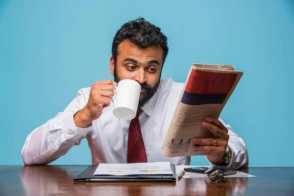 Foto med speciell effekt visar indisk ung affärsman läsa tidningen samtidigt ha kaffe på kontoret, Asiatiska affärsman njuter kaffe medan du läser nyheter publikation — Stockfoto