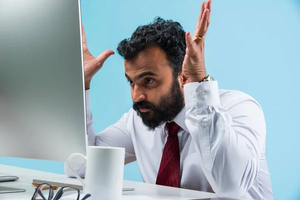 Frustrerad indisk ung affärsman med skägg visar sorgligt uttryck i kontoret på datorbord — Stockfoto