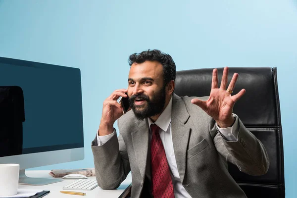Młody biznesmen indyjskiego w brodę zajęty na telefon podczas korzystania z laptopa lub komputera w biurze, Azjatycki biznes biznesmen rozmowy za pomocą smartfona — Zdjęcie stockowe