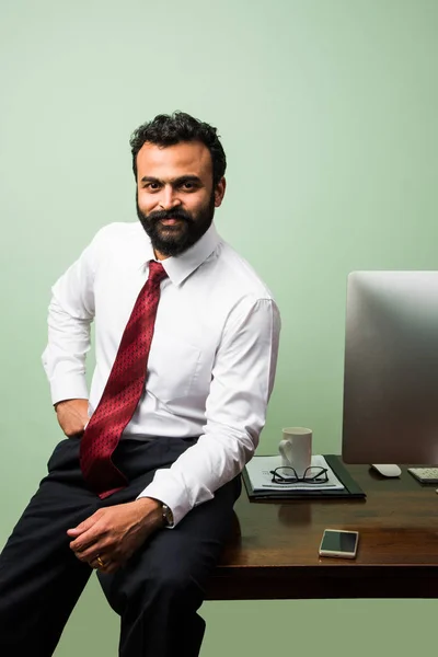 Portrét mladé indický podnikatel v vousy, sedí v uvolněné pozici u stolu office s příjemný vzhled. Jistý asijský mužské podnikatel — Stock fotografie