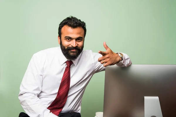 Retrato de joven empresario indio en barba, sentado en posición relajada en la mesa de la oficina con aspecto agradable. Confiado asiático hombre de negocios persona — Foto de Stock