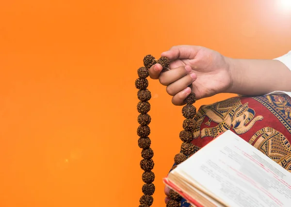 closeup picture of hand while doing Meditation with rudraksha mala or rosary beads