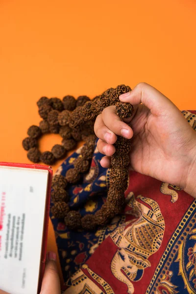 closeup picture of hand while doing Meditation with rudraksha mala or rosary beads