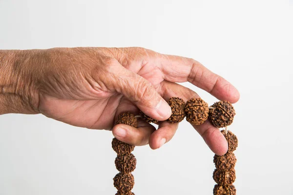 closeup picture of hand while doing Meditation with rudraksha mala or rosary beads