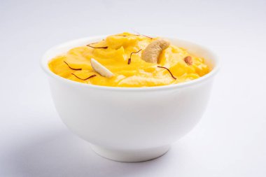 hapus or alphonso Mango pudding / Mango shrikhand or srikhand or amrakhand - Mango dessert with condensed milk magoes and nuts, selective focus over white background clipart