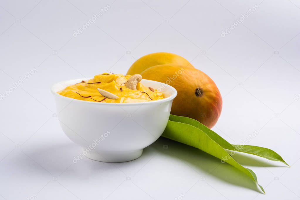 hapus or alphonso Mango pudding / Mango shrikhand or srikhand or amrakhand - Mango dessert with condensed milk magoes and nuts, selective focus over white background