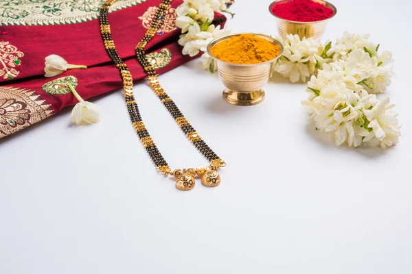 Close-up foto af en Mangalsutra eller halskæde til båret af en gift hindu kvinder, med traditionelle saree eller paithani med huldi kumkum og mogra blomster eller Jasminum sambac krans - Stock-foto