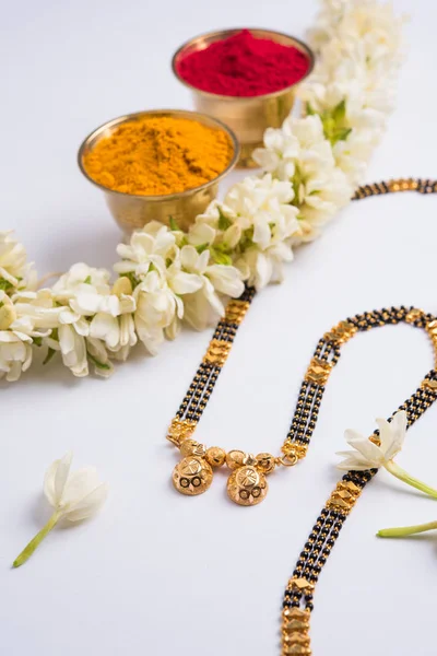 Foto de cerca de un Mangalsutra o collar para llevar por una mujer hindú casada, con saree tradicional o paithani con flores de huldi kumkum y mogra o guirnalda de sambac de jazmín — Foto de Stock