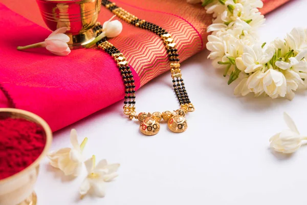 Foto de close-up de um Mangalsutra ou colar para usado por uma mulher hindu casada, com saree tradicional ou paithani com flores huldi kumkum e mogra ou jasminum sambac guirlanda — Fotografia de Stock