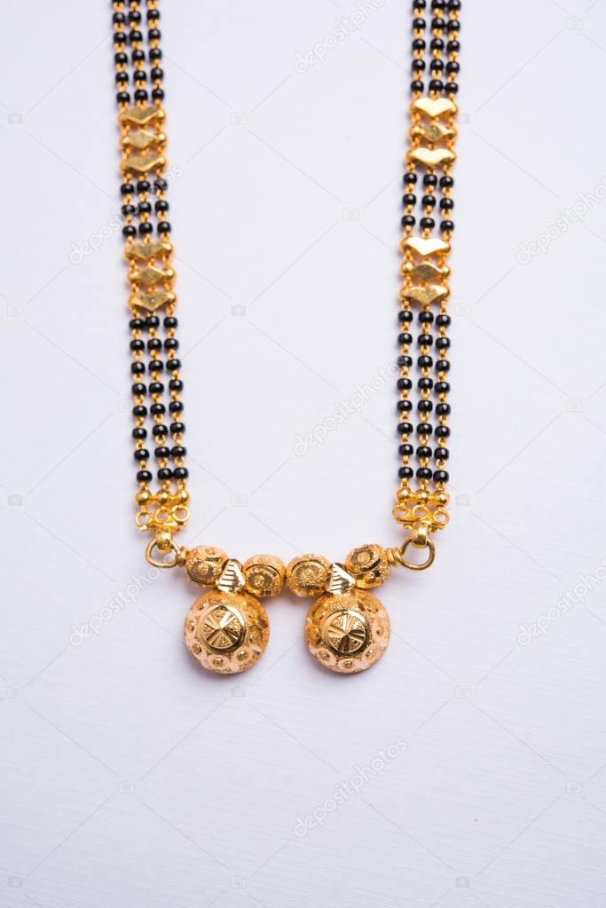 close-up photo of a Mangalsutra or necklace to worn by a married hindu women, with huldi kumkum and mogra flowers or Jasminum sambac garland over white background