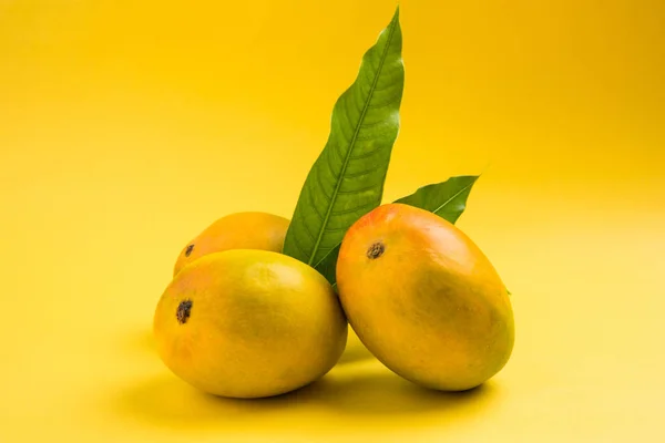 Rey de frutas; Alphonso amarillo Dúo de frutas de mango con tallos y hojas verdes aisladas sobre fondo blanco en una canasta de caña, un producto de Konkan de Maharashtra - India — Foto de Stock