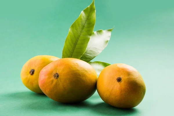 König der Früchte; alphonso gelbe Mango-Frucht-Duo mit Stielen und grünem Blatt isoliert auf weißem Hintergrund in einem Korb aus Zuckerrohr, ein Produkt von Konkan aus Maharashtra - Indien — Stockfoto