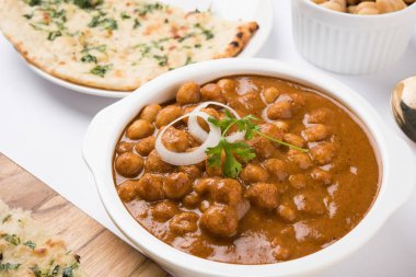 Baharatlı piliç bezelye köri veya Çola Masala veya Chana Masala veya chole bhature veya choley dilimlenmiş soğan ve yeşil kişniş yaprağı, seçici odak ile süslenmiş