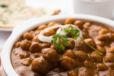 Baharatlı piliç bezelye köri veya Çola Masala veya Chana Masala veya chole bhature veya choley dilimlenmiş soğan ve yeşil kişniş yaprağı, seçici odak ile süslenmiş
