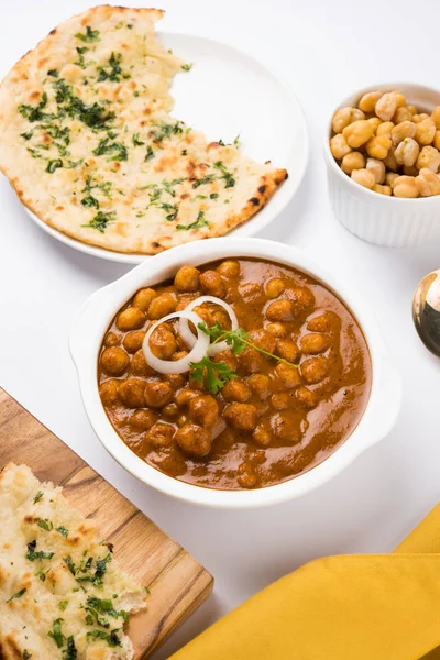 Πικάντικο γκόμενα αρακάς κάρυ ή Chola Masala ή Chana Masala ή chole bhature ή choley γαρνιρισμένο με φέτες κρεμμύδι και πράσινη κόλιανδρο φύλλο, επιλεκτική εστίαση — Φωτογραφία Αρχείου