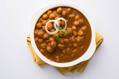 Baharatlı piliç bezelye köri veya Çola Masala veya Chana Masala veya chole bhature veya choley dilimlenmiş soğan ve yeşil kişniş yaprağı, seçici odak ile süslenmiş