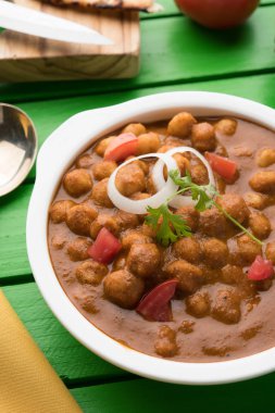 Baharatlı piliç bezelye köri veya Çola Masala veya Chana Masala veya chole bhature veya choley dilimlenmiş soğan ve yeşil kişniş yaprağı, seçici odak ile süslenmiş