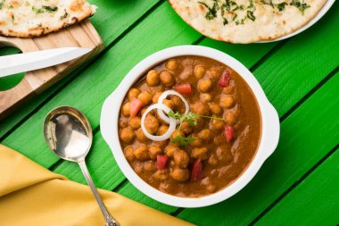 Baharatlı piliç bezelye köri veya Çola Masala veya Chana Masala veya chole bhature veya choley dilimlenmiş soğan ve yeşil kişniş yaprağı, seçici odak ile süslenmiş