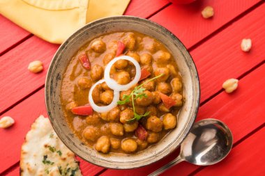 Baharatlı piliç bezelye köri veya Çola Masala veya Chana Masala veya chole bhature veya choley dilimlenmiş soğan ve yeşil kişniş yaprağı, seçici odak ile süslenmiş