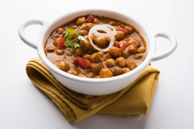 Baharatlı piliç bezelye köri veya Çola Masala veya Chana Masala veya chole bhature veya choley dilimlenmiş soğan ve yeşil kişniş yaprağı, seçici odak ile süslenmiş