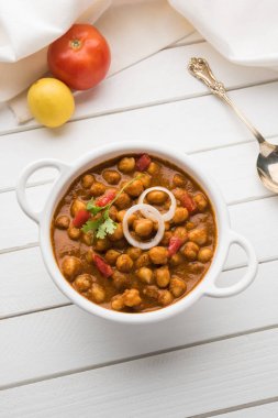 Baharatlı piliç bezelye köri veya Çola Masala veya Chana Masala veya chole bhature veya choley dilimlenmiş soğan ve yeşil kişniş yaprağı, seçici odak ile süslenmiş